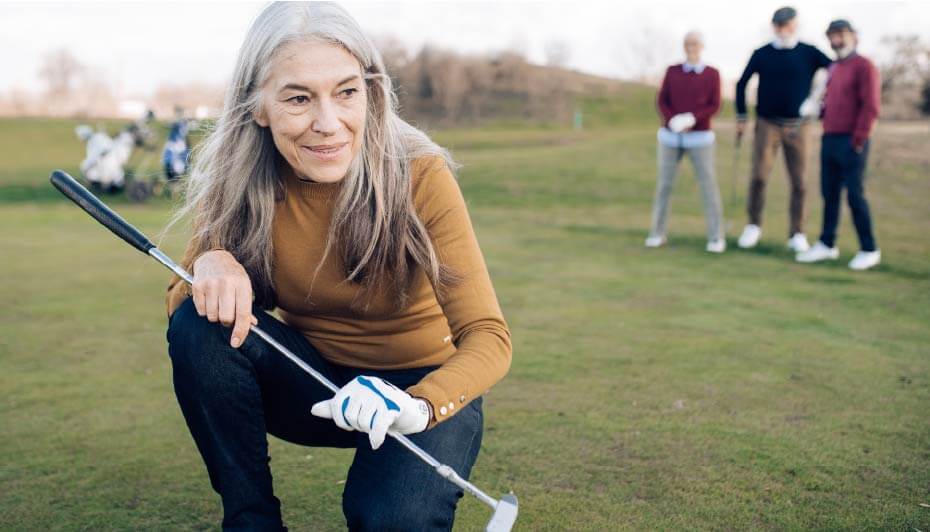 mature woman golfing with friends watching in background