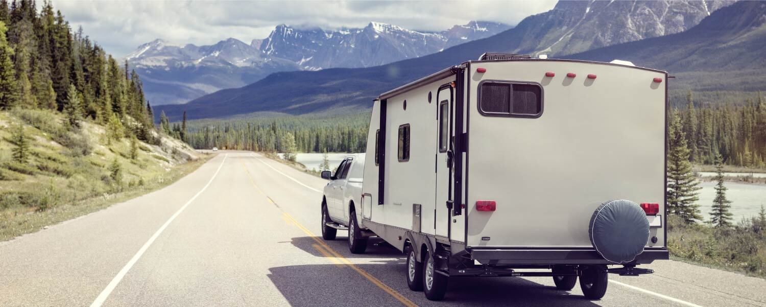 rv trailer hitched to truck on road and mountains